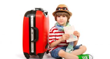 ילדים יושב ומחזיק דרכון פורטוגלי ומזוודה אדומה לידו